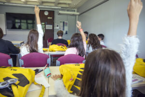 Studenti che alzano la mano in classe
