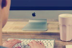 Persona che scrive alla tastiera di un Mac