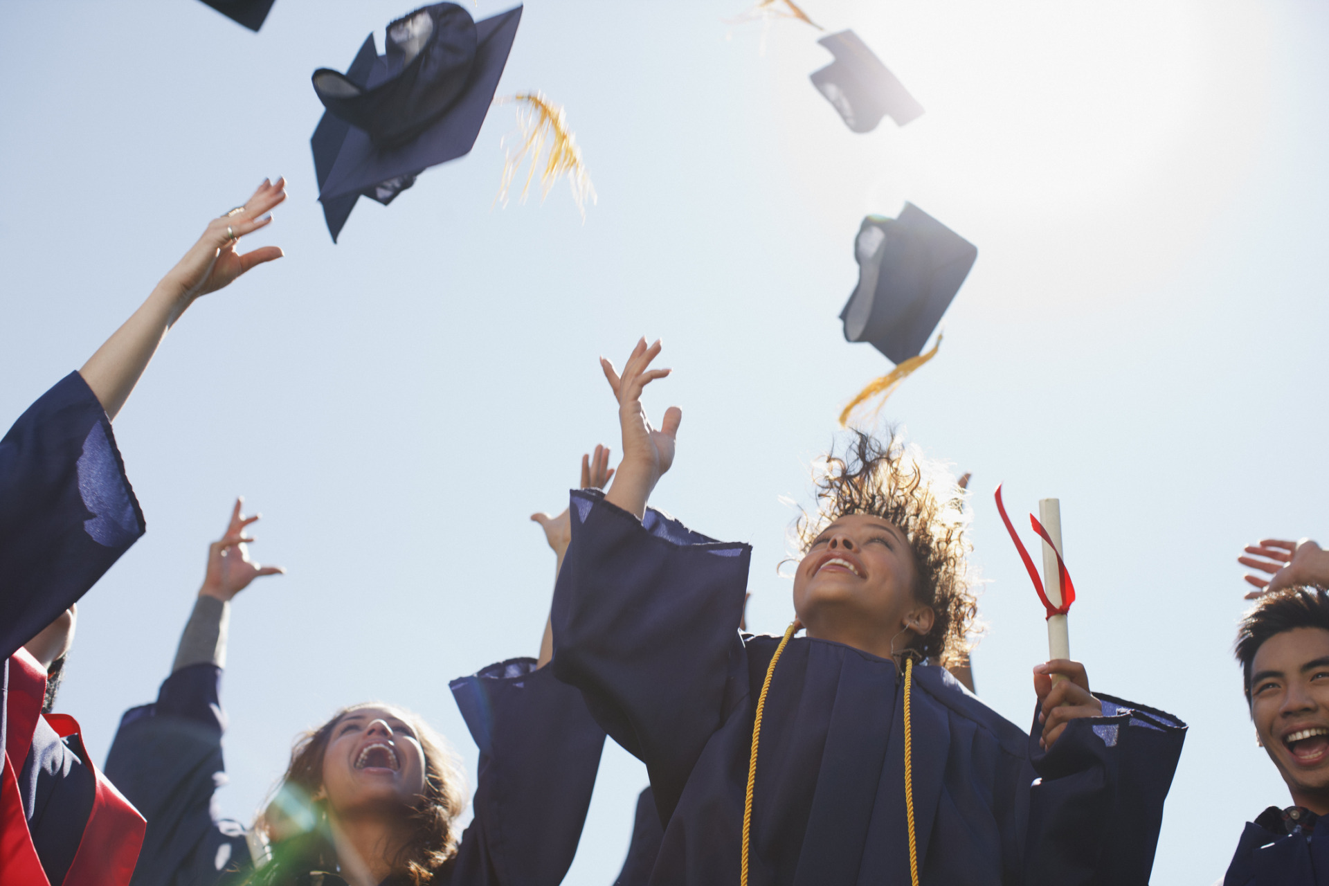 Studenti laureati che lanciano in aria il tocco accademico