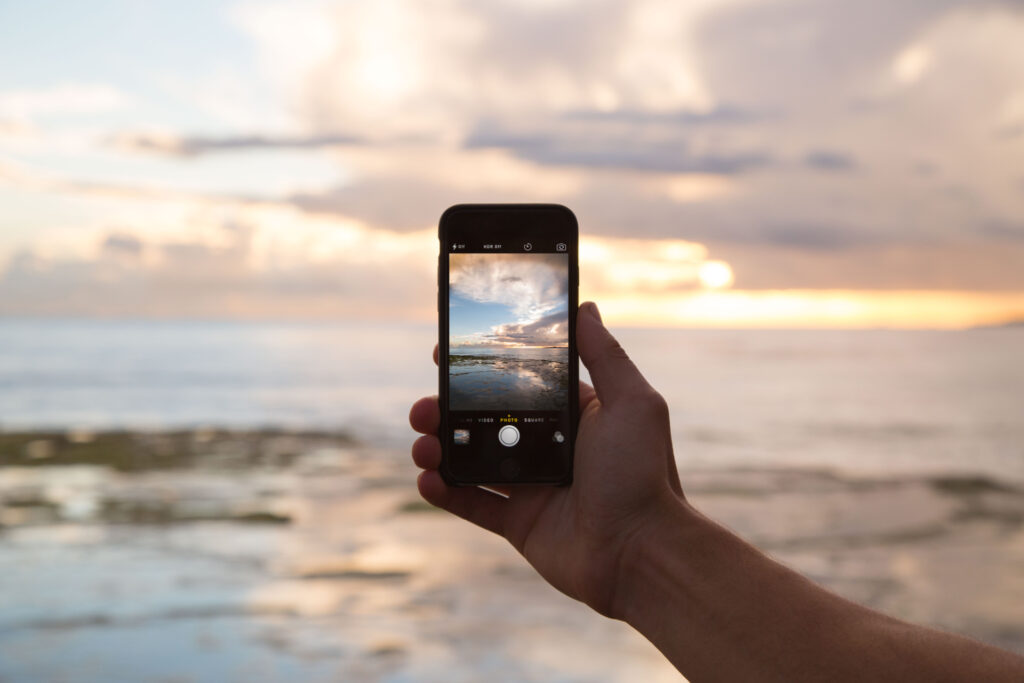 mano con un cellulare che scatta una foto al tramonto