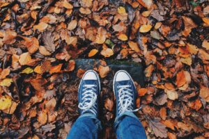 Piedi co sneakers ripresi dall'alto sul foglie autunnali