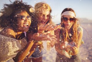 tre ragazze su una spiaggia si divertono soffiando la sabbia