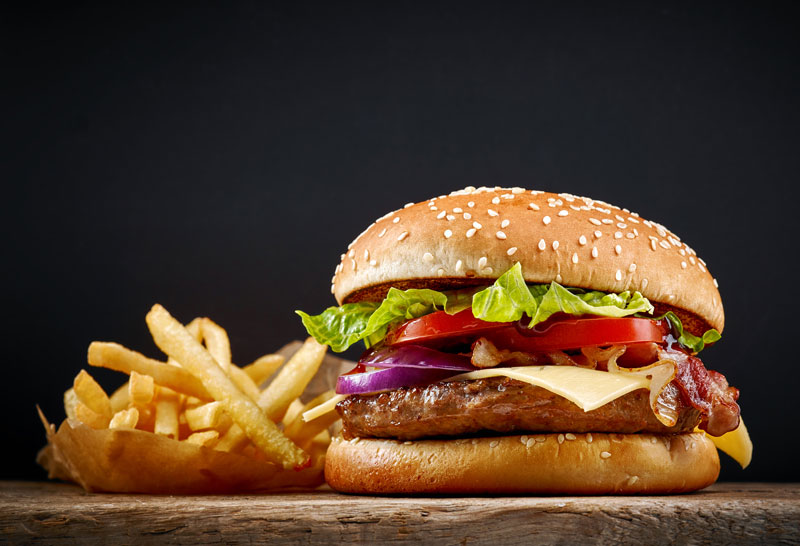 Panino con hamburger, cipolle e pomodori e patatine fritte